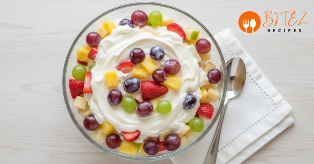 Fruit pudding salad with vanilla pudding and mixed fruits in a glass bowl.